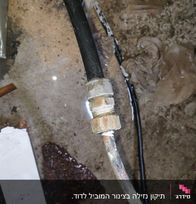 צינור מים עם חיבור מתכת על רצפה רטובה